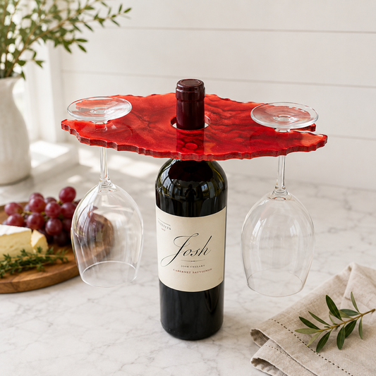 Handcrafted red resin wine glass holder displayed on a wine bottle with two stemmed glasses